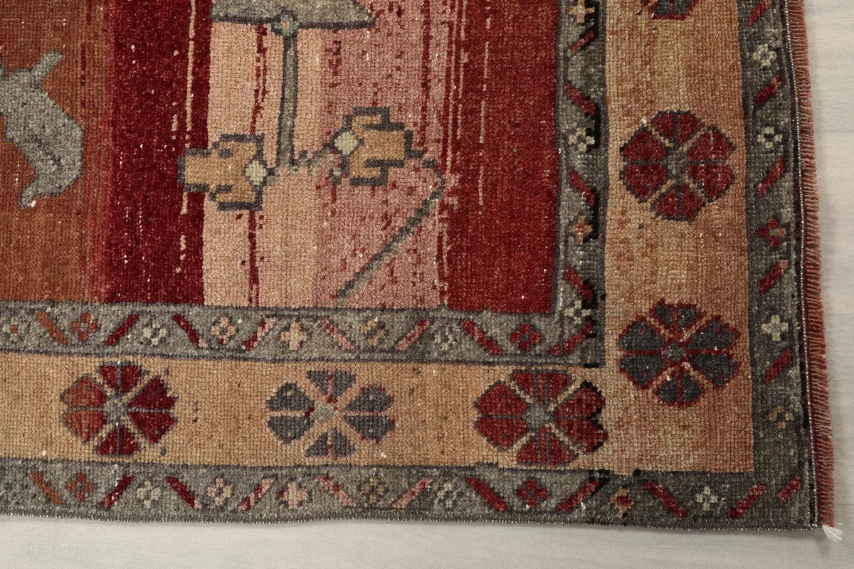 Detail of the rug's border with floral-like patterns and the red field