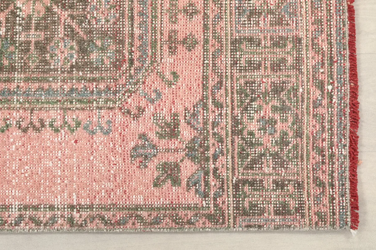 Detailed view of the rug's end, showcasing the patterned border and the rose main field.
