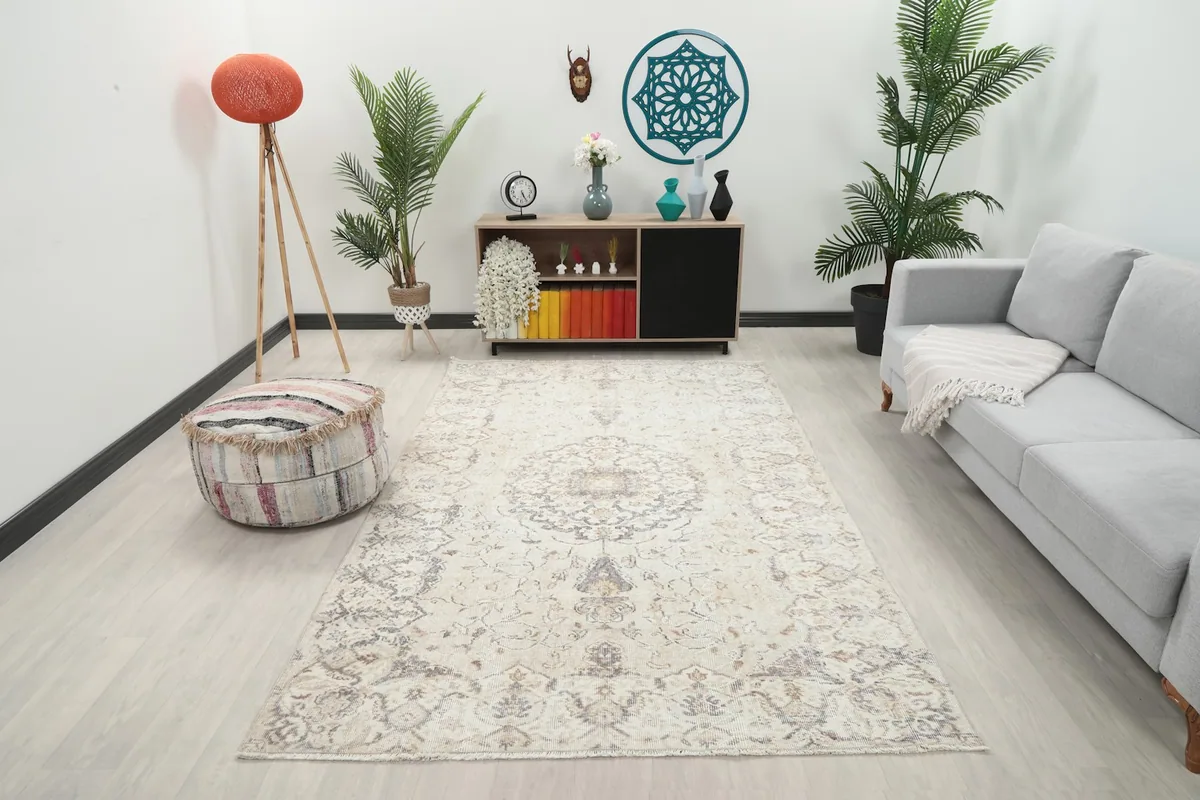 Ivory and gray vintage rug placed in a living room setting, viewed from a wide angle.