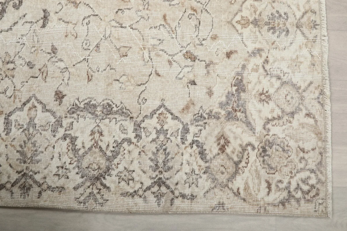 Detail of the rug's border pattern in gray and beige tones.