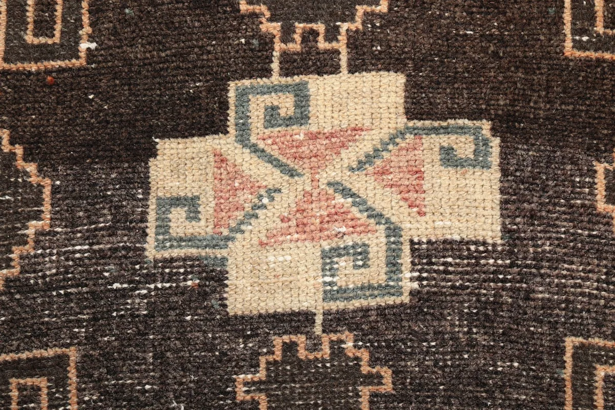 Tight close-up of a single central geometric motif, highlighting the wool texture and colors.