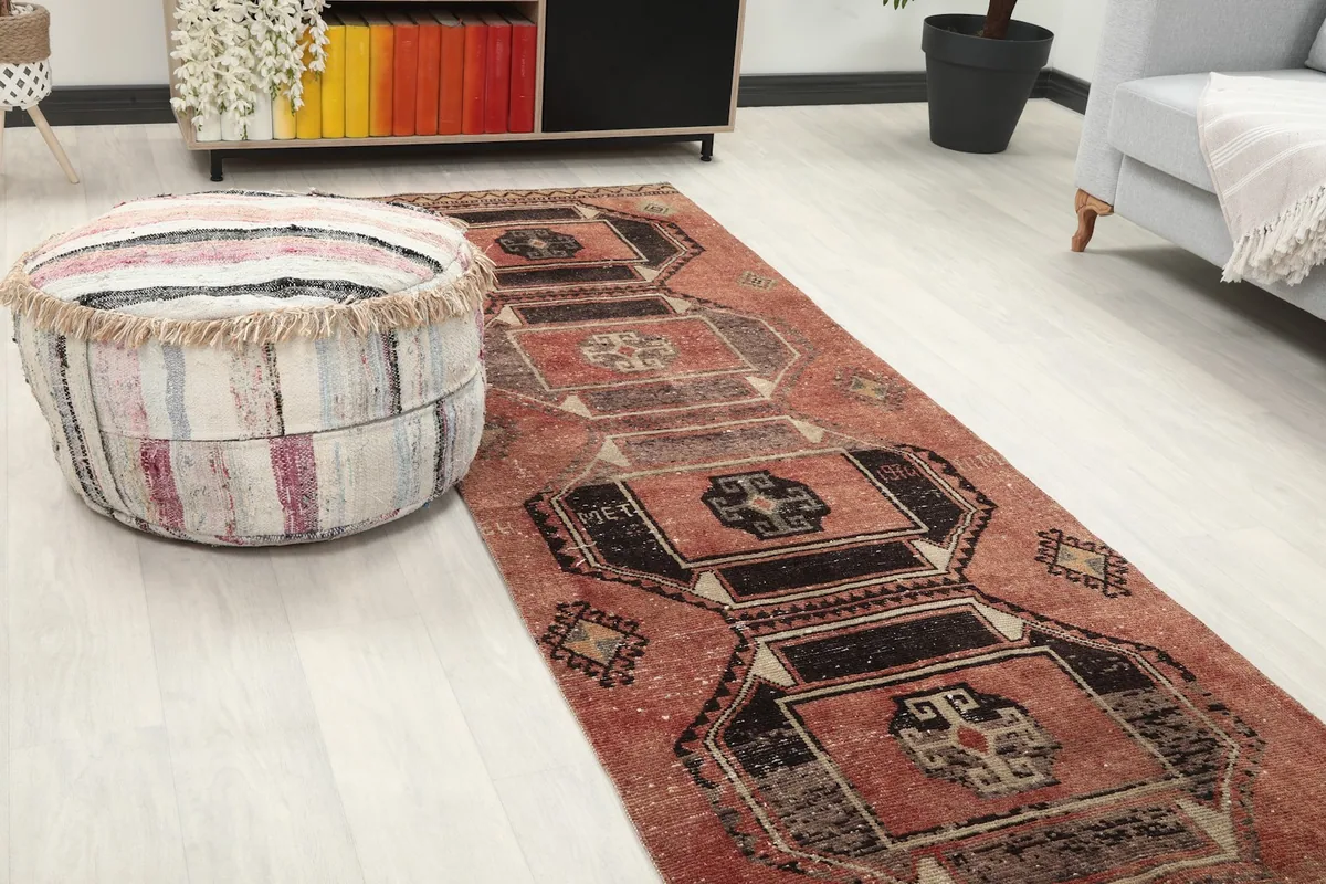 Close-up angle showing the rug's rust color and geometric patterns next to a striped ottoman