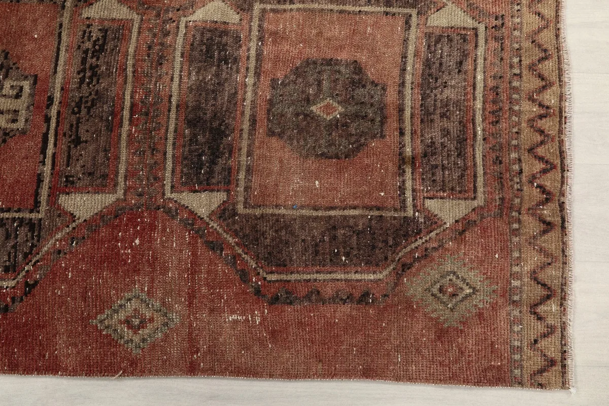 Detailed view of the rug's border and a faded geometric motif in rust and beige