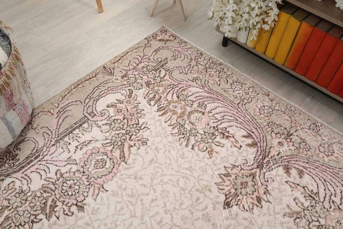Corner angle view of the rug, showing the blend of ivory, rose, and beige colors