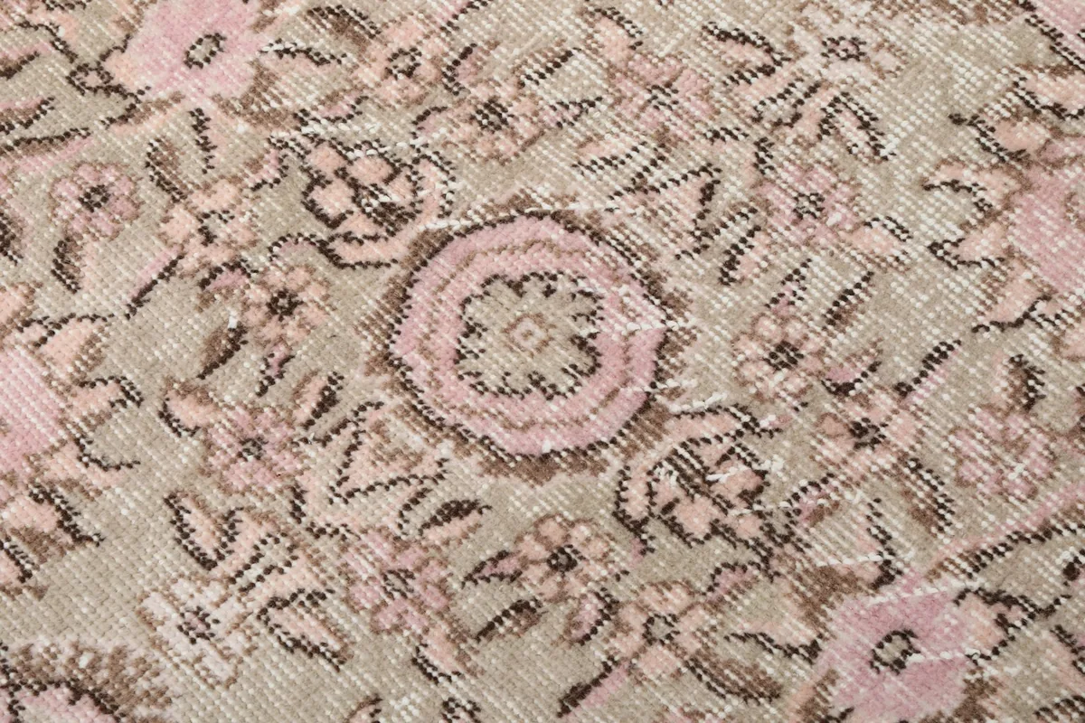 Macro detail of the hand-knotted wool pile and intricate floral patterns in rose and brown