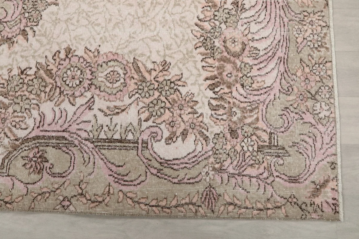 Detail of the rug's floral border design with rose and beige tones