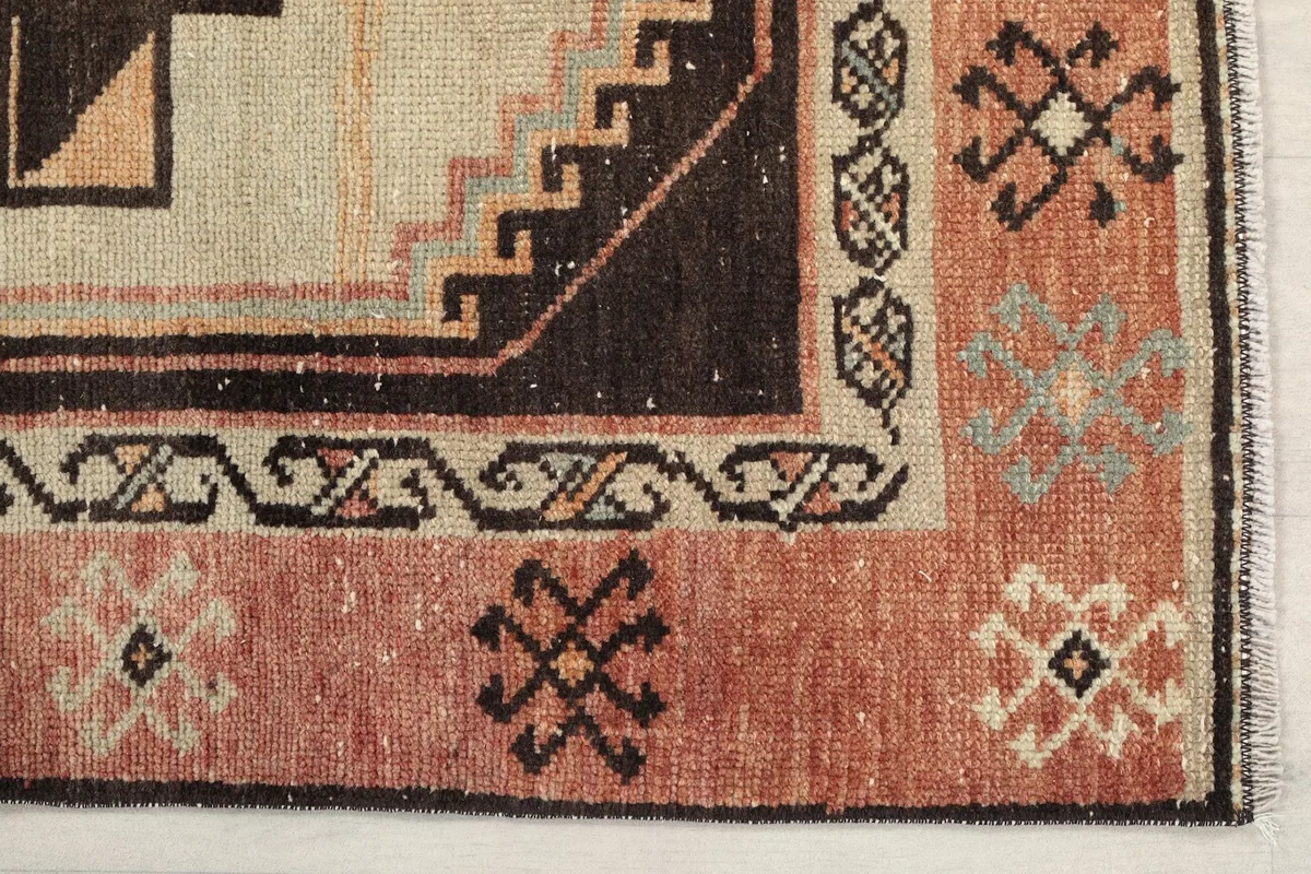 Detailed view of the rug's corner, showing tribal motifs in the rust border