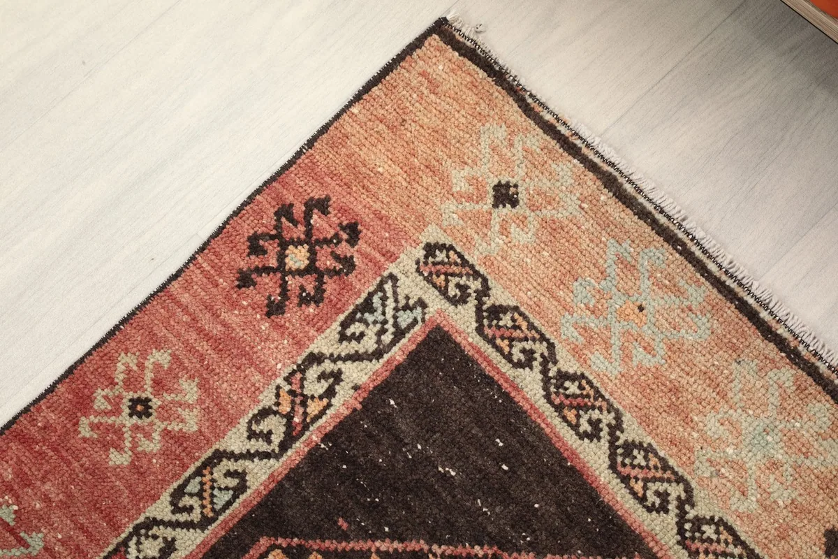 Corner detail of the rug's rust border with small tribal symbols and brown accents