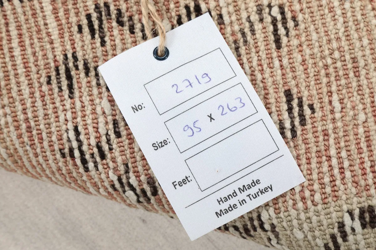 Close-up of the rug's tag, displaying its size in centimeters and 'Hand Made in Turkey'
