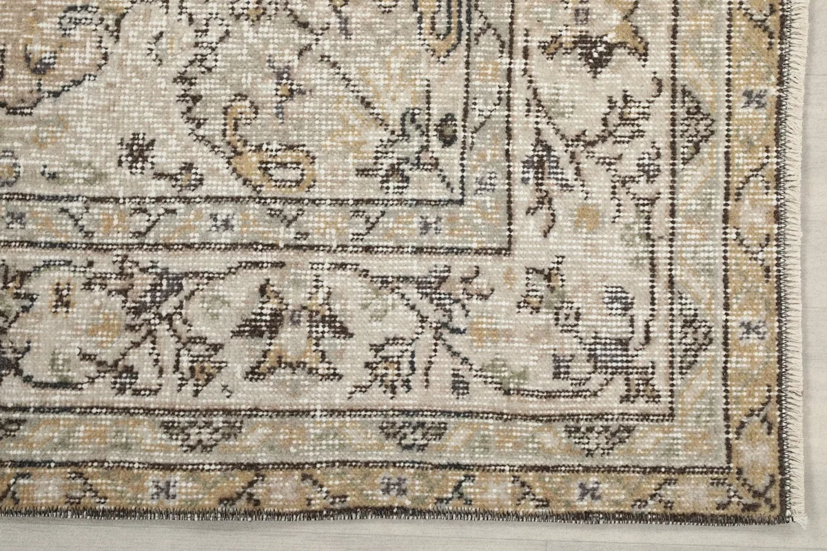 Detailed view of the rug's border design with floral-geometric motifs in charcoal and tan