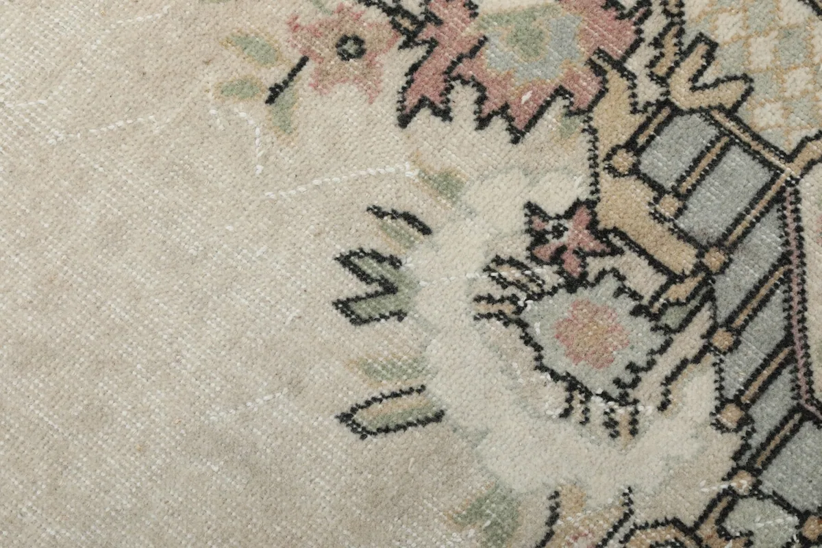 Extreme close-up of the rug's low wool pile and the fine details of the hand-knotted pattern.