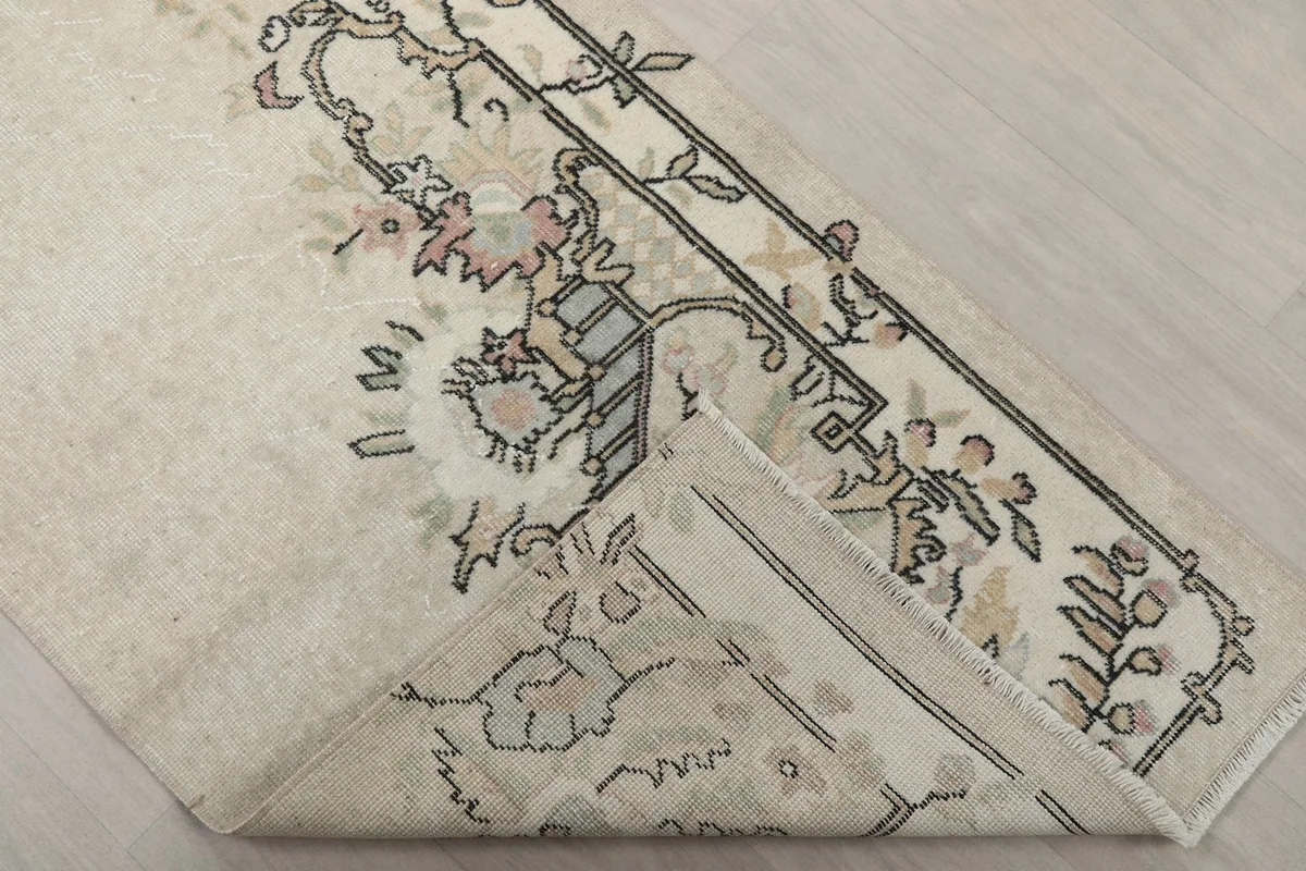 Corner of the rug folded back, revealing the backside of the hand-knotted wool pile and cotton foundation.