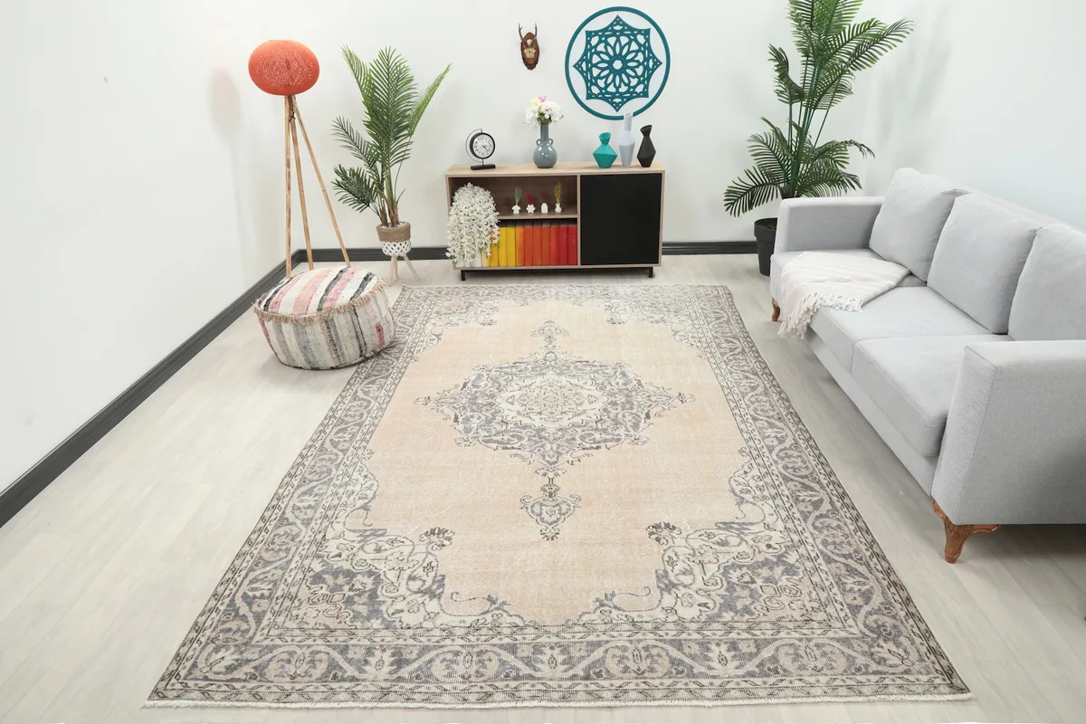 Ivory and gray vintage Anatolian rug displayed in a bright living room setting with a sofa and plants