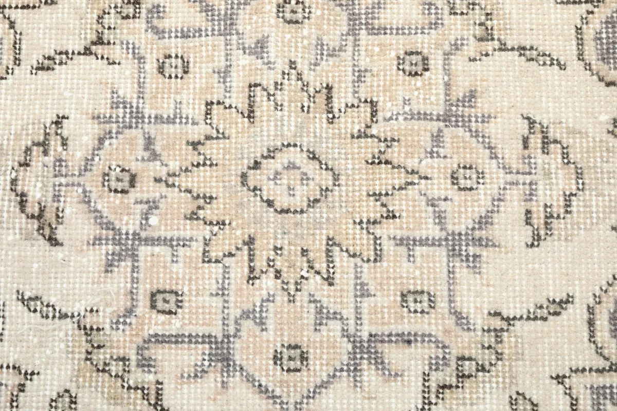 Intricate detail of the gray and ivory patterns within the central medallion of the vintage rug