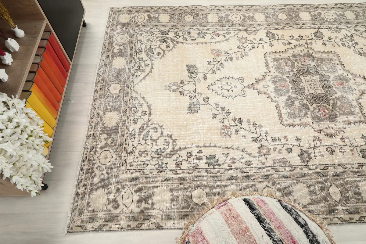 Angled shot of the rug's upper section, showing the faded floral elements and border.
