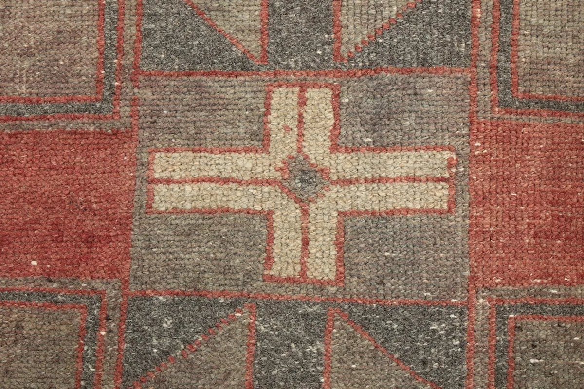Detailed view of the cross-like tribal motif in beige, rust, and black within the gray field