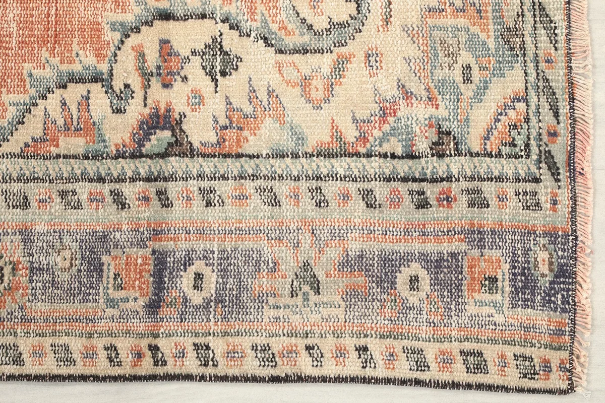 Detail of the rug's blue and ivory geometric border pattern with rust accents