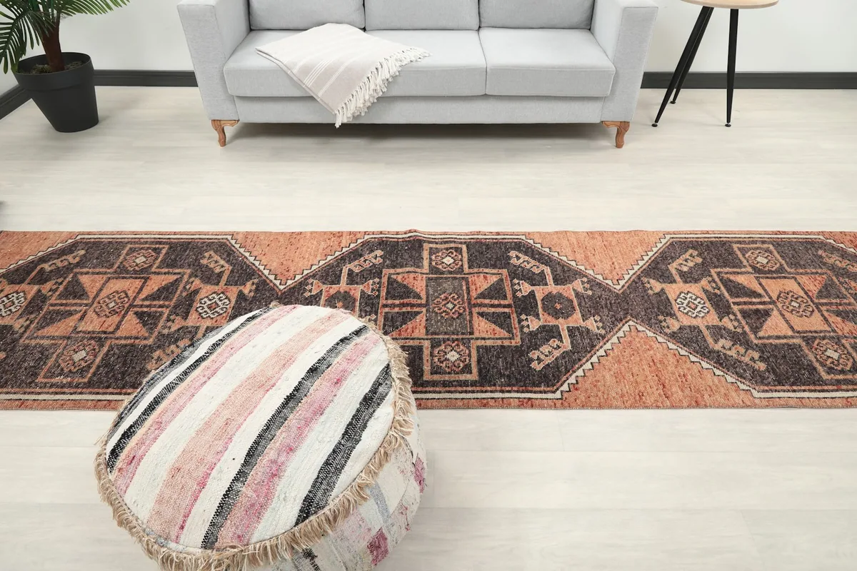 Full view of the runner rug from above, placed in a room with a sofa and pouf, showcasing its scale