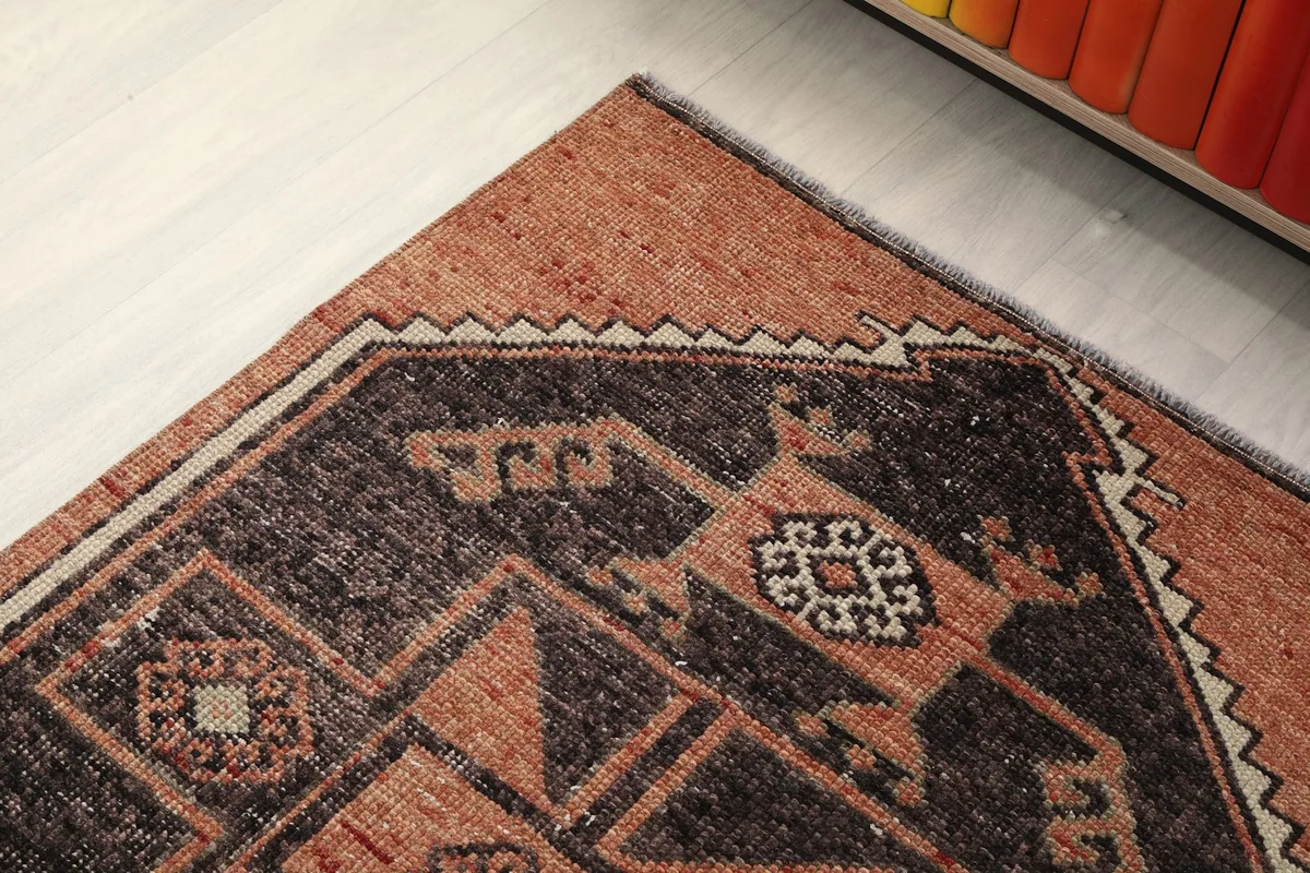 Close-up of the rug's edge, highlighting the subtle border design and the transition from charcoal to rust