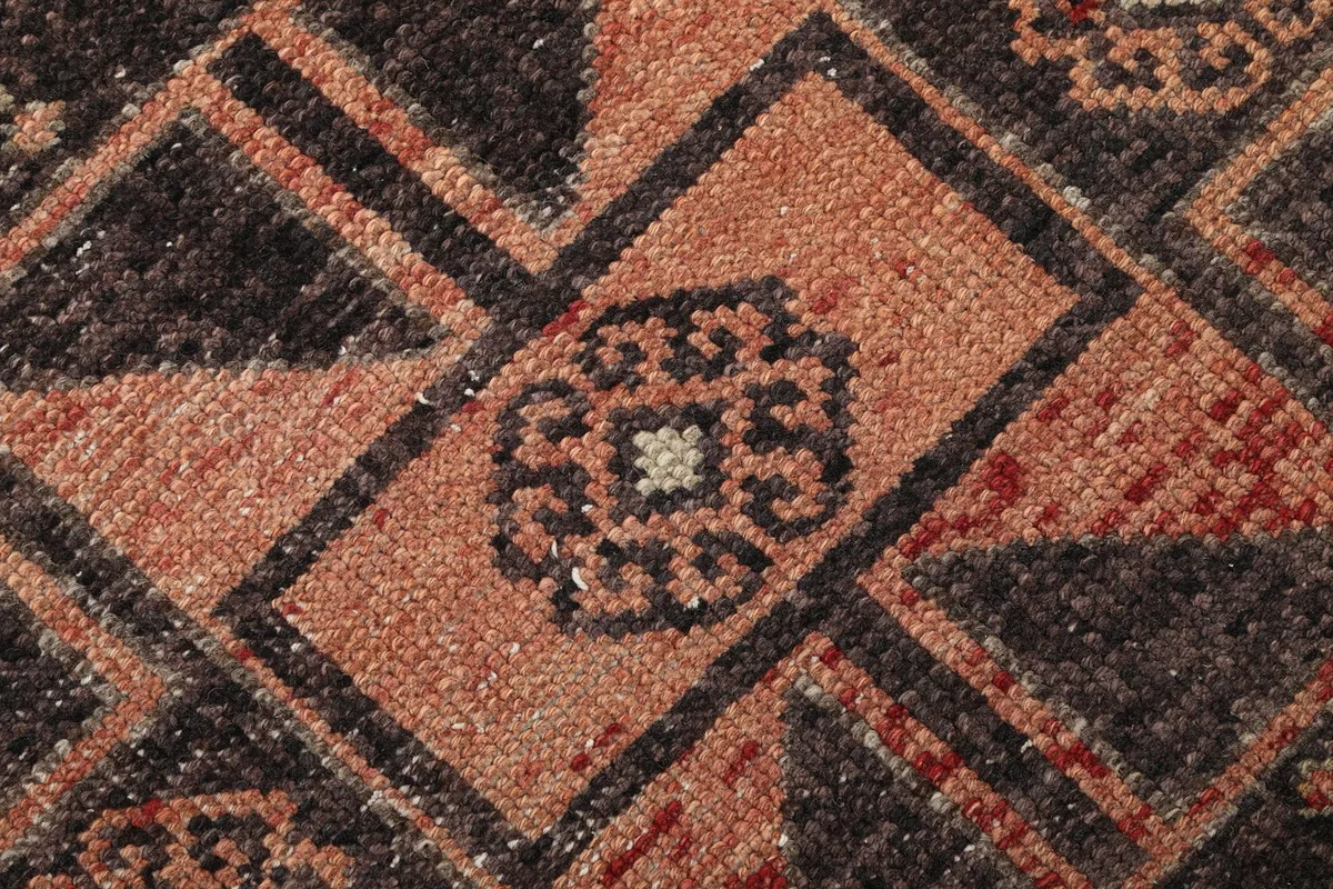 Macro close-up of the low wool pile, revealing the texture and intricate knotting of the geometric pattern