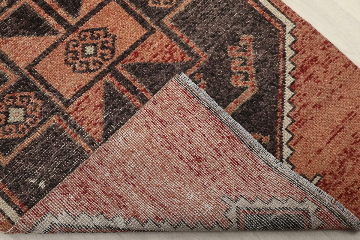 Corner of the rug folded back to reveal the cotton foundation and the reverse side of the hand-knotted wool