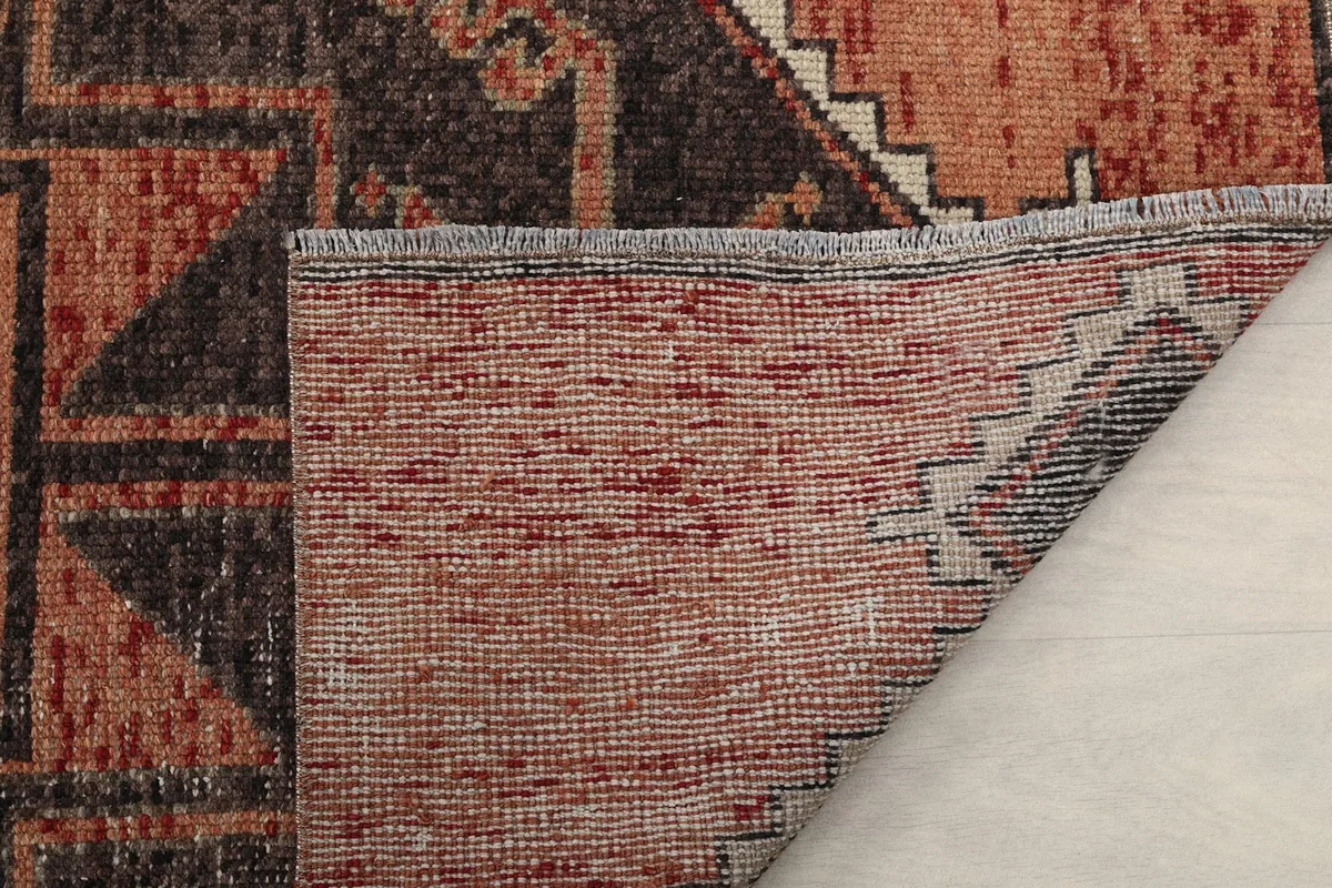 Close-up of the rug's end, showing the short, natural cotton fringe and the back of the rug