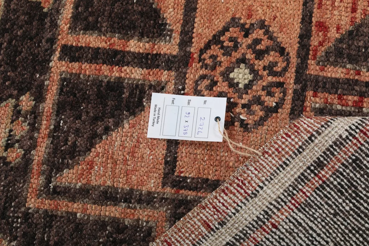 Detail of the rug's back with a product tag, showing the hand-knotted construction and material