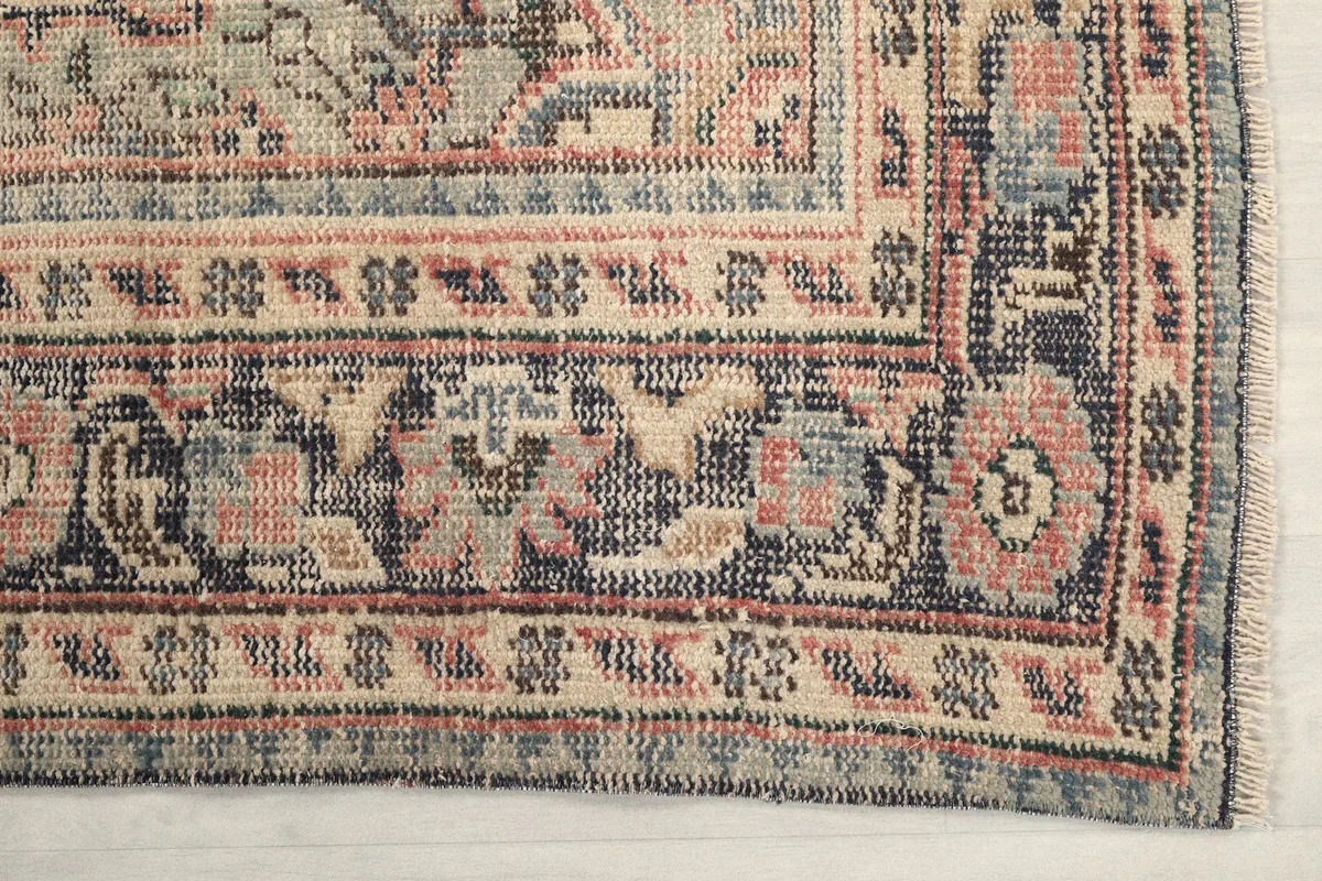 Detailed corner view of the rug's intricate navy and beige border patterns