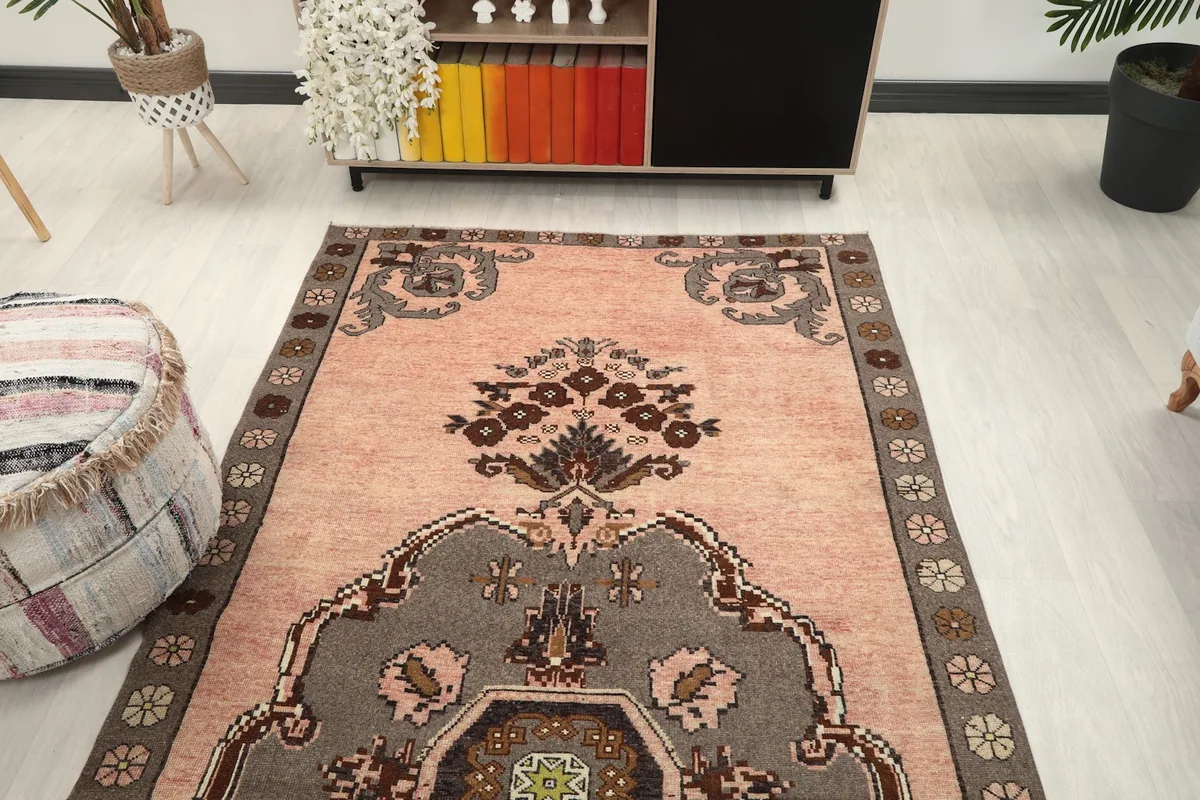 View from one end of the rose Anatolian rug, showcasing the medallion and upper floral motif