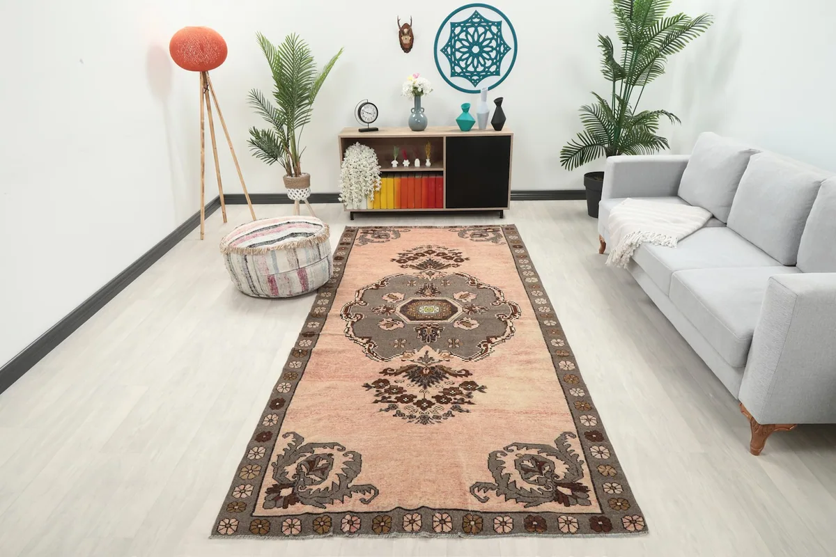 Vintage rose Anatolian rug in a modern living room setting with a gray sofa and plants