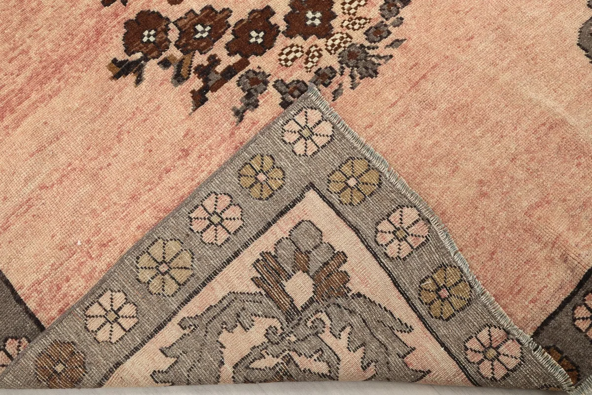 Corner of the rug folded back to reveal the hand-knotted cotton foundation and pile structure