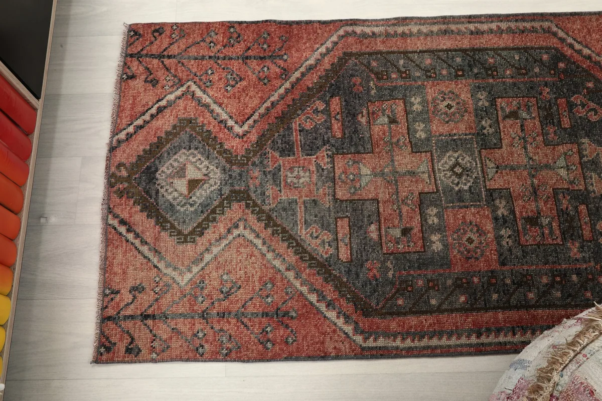 Angled view of the rug's patterns and colors, emphasizing the rust and charcoal tones