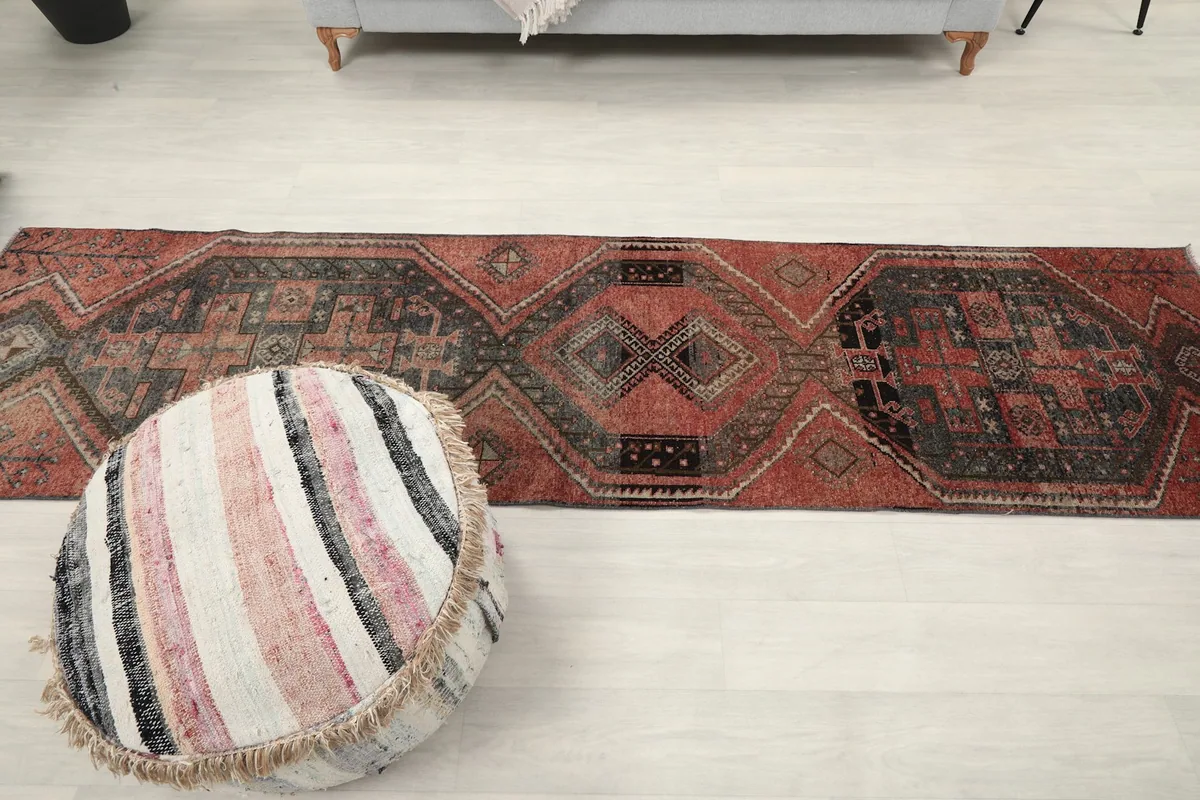 Overhead view of the long runner rug in a room, next to a striped pouf, showing its full length