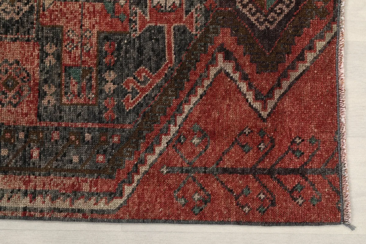 Detailed view of the rug's border and a section of the rust field with subtle wear