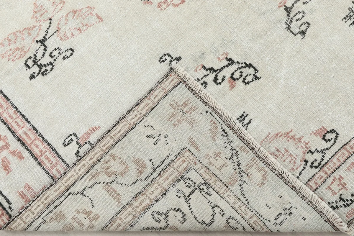 Folded corner revealing the back of the hand-knotted cotton foundation.