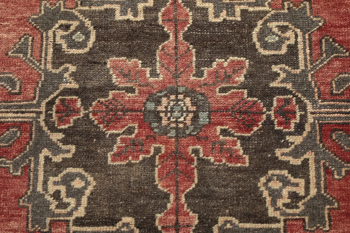 Intricate detail of a floral-geometric motif in rust, charcoal, and blue on the runner
