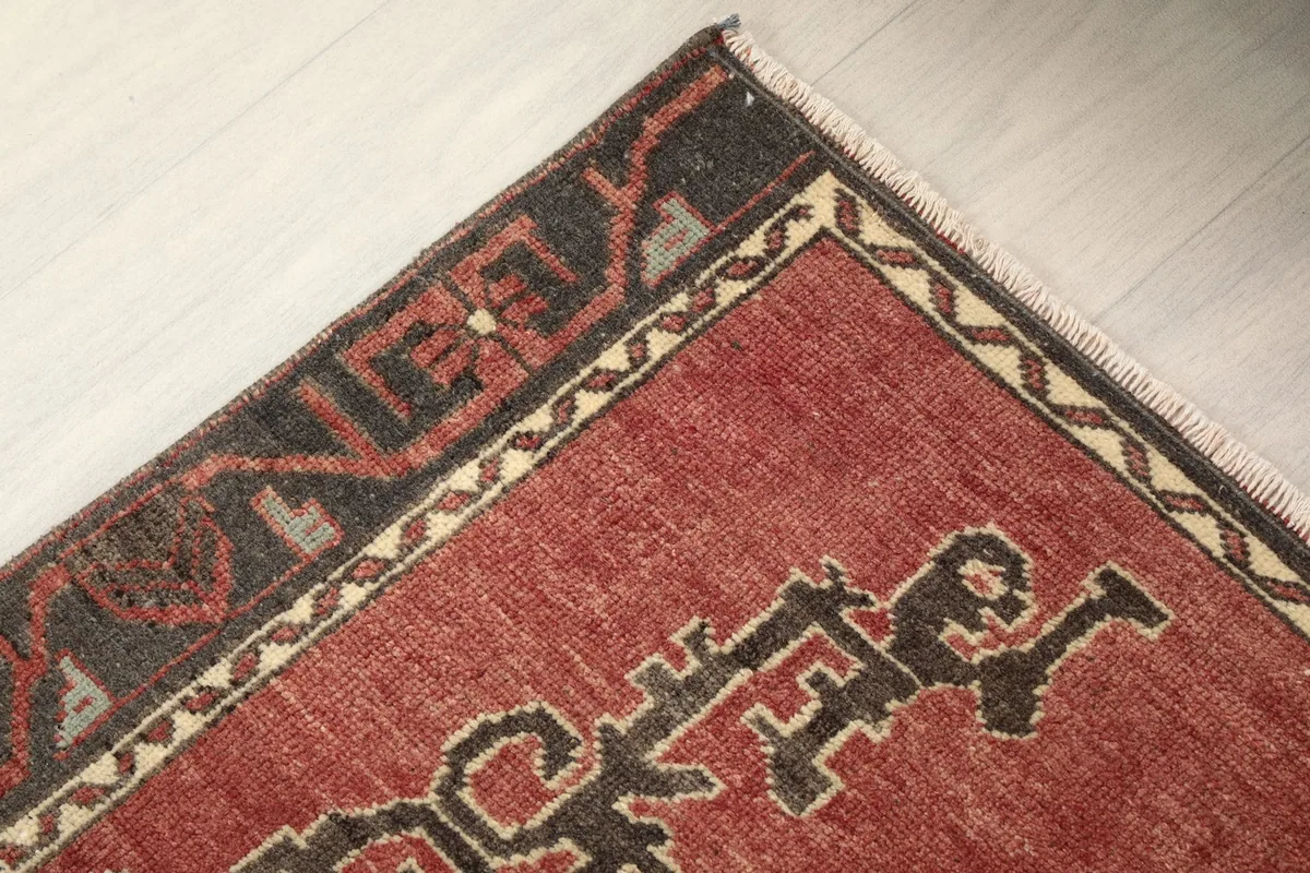 Corner detail of the rug showing the charcoal border with geometric patterns and fringe