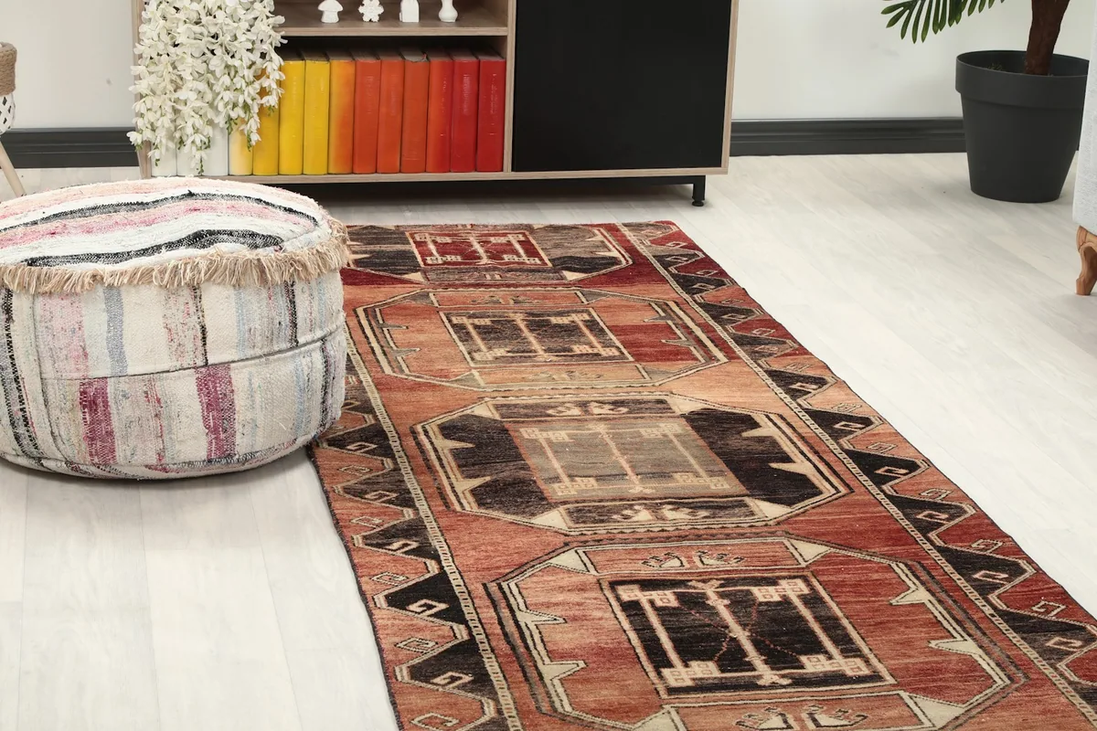 Close-up view of the rust runner rug's geometric pattern next to a pouf