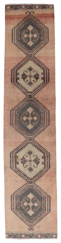 Full overhead view of the rose and gray geometric tribal runner rug on a white background.