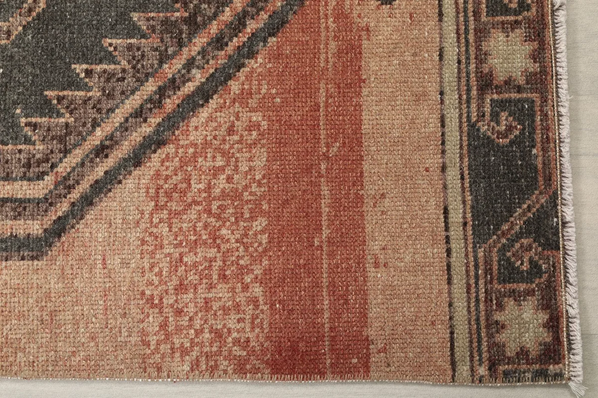 Detail shot of the rug's rose field and border with a subtle color variation and wear.