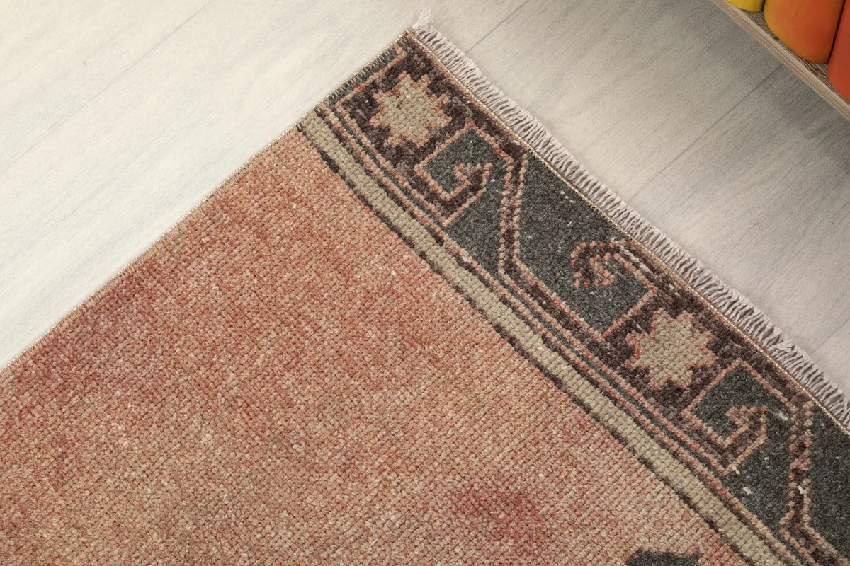 Close-up of the rug's border, featuring a gray band with star-like motifs and fringe.
