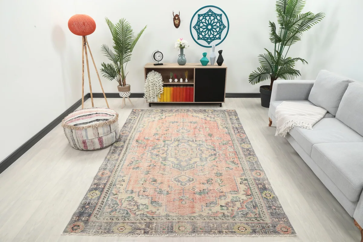 Vintage Anatolian rose and gray rug placed in a living room setting with a light gray sofa and wooden cabinet.