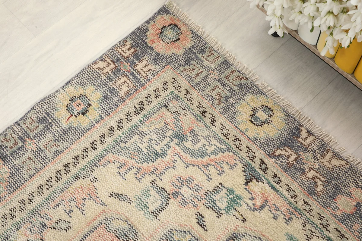 Corner detail of the rug, showing the blend of rose, gray, ivory, and subtle green and yellow colors.