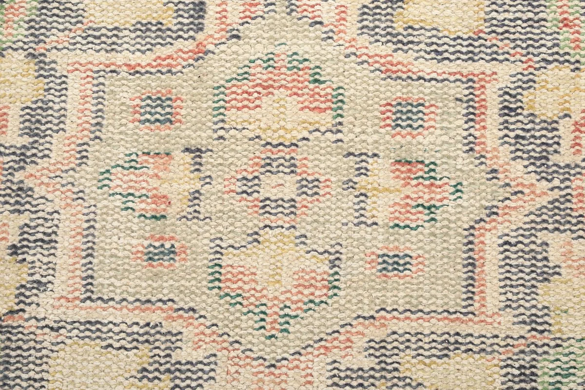 Macro view of the hand-knotted wool pile, revealing the intricate weaving and colors of the rug's pattern.