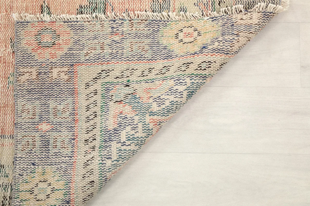 Corner detail of the rug's back, showing the fringes and the tight weave of the cotton foundation.