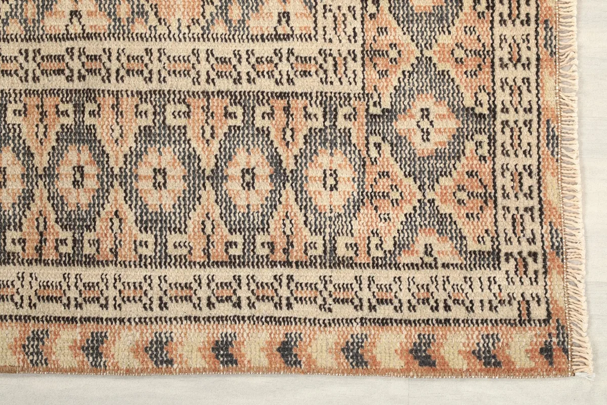 Corner detail of the rug showing the intricate charcoal and beige border patterns