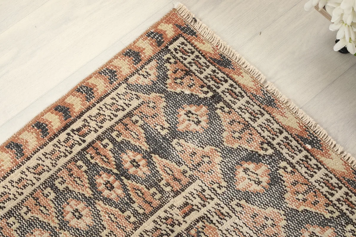 Detailed view of the rug's border, featuring charcoal and orange geometric designs
