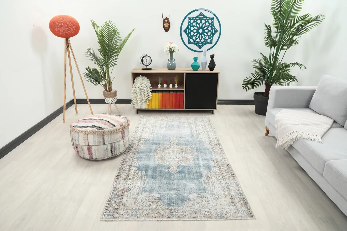 Vintage blue medallion rug in a living room setting with a light sofa and pouf