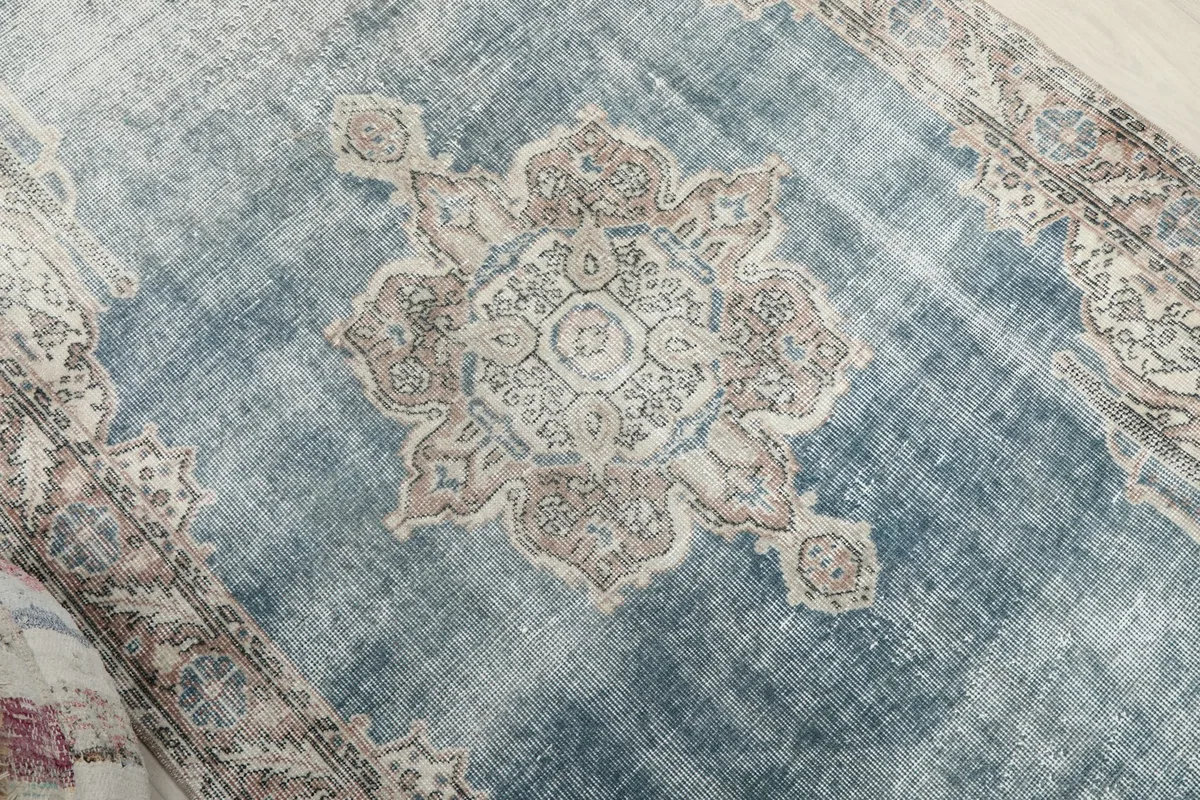 Close-up of the central medallion with faded blue and ivory tones