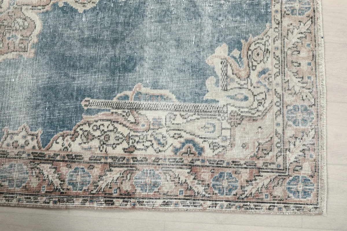 Detail of the rug's corner, showing the faded blue field and intricate border patterns